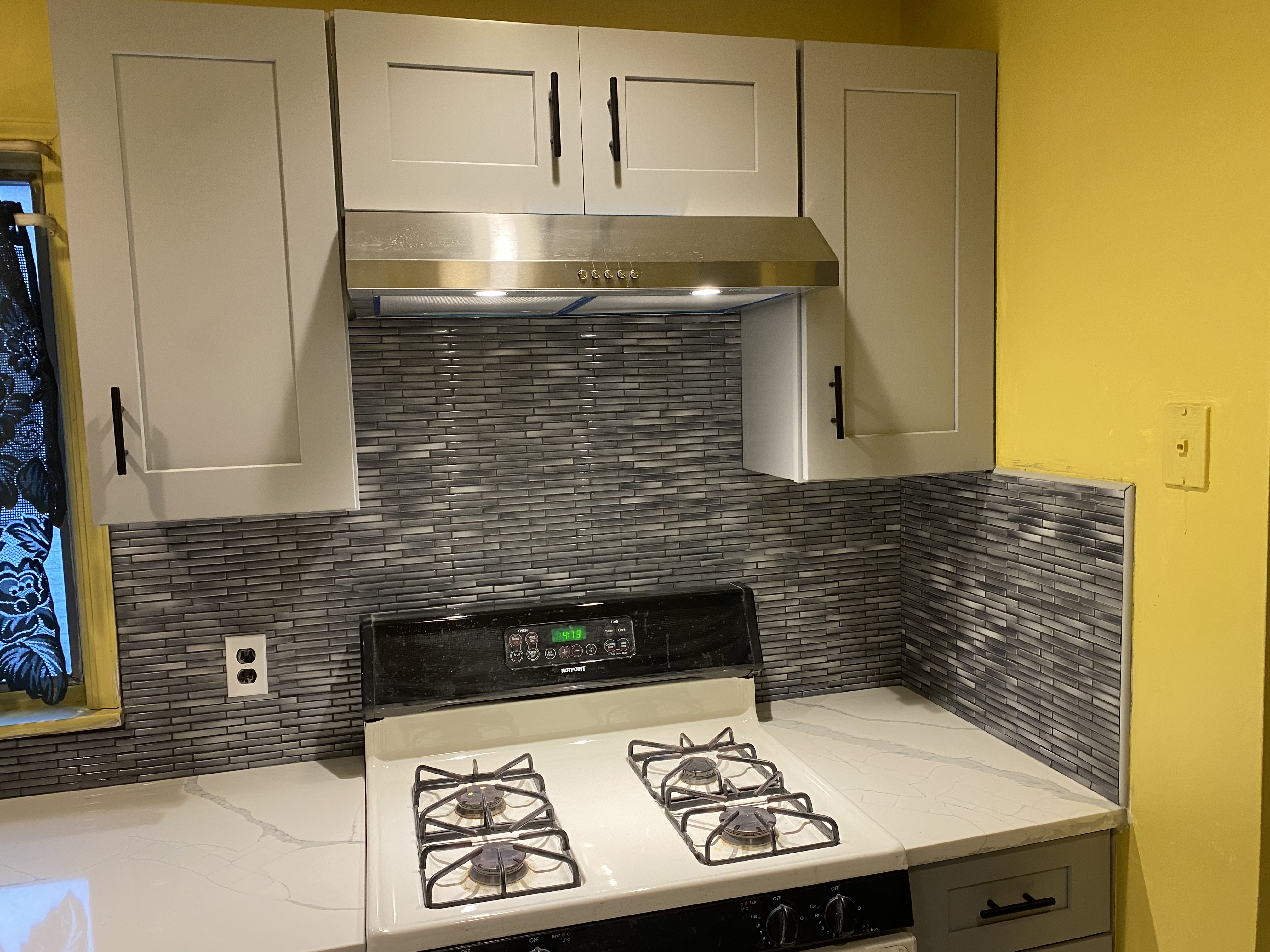 Kitchen with gray cabinets and mosaic backsplash